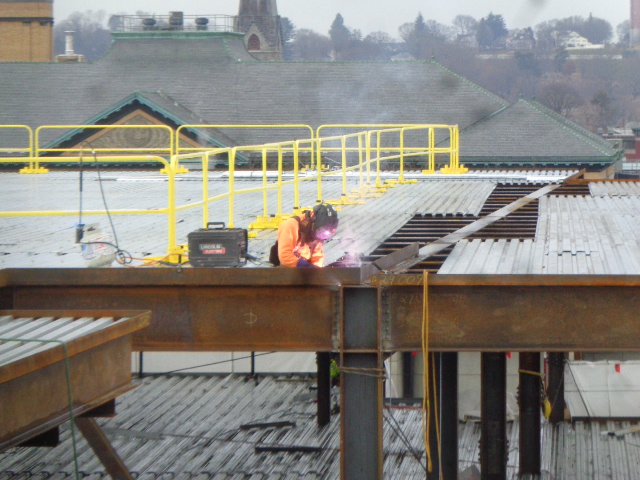construction workers welding metal edge to structure beam