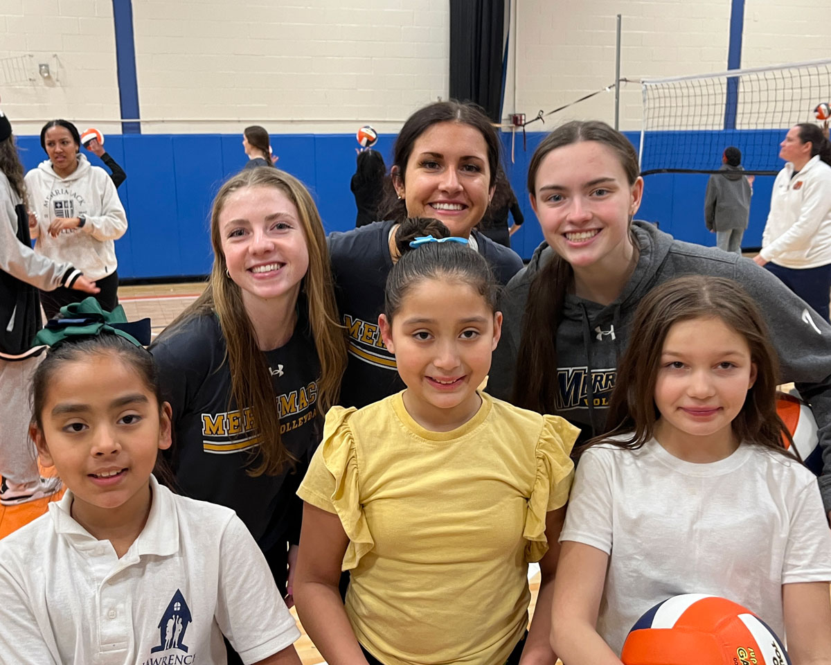 Lawrence female students posing with volleyball with Merrimack College female Volleyball players