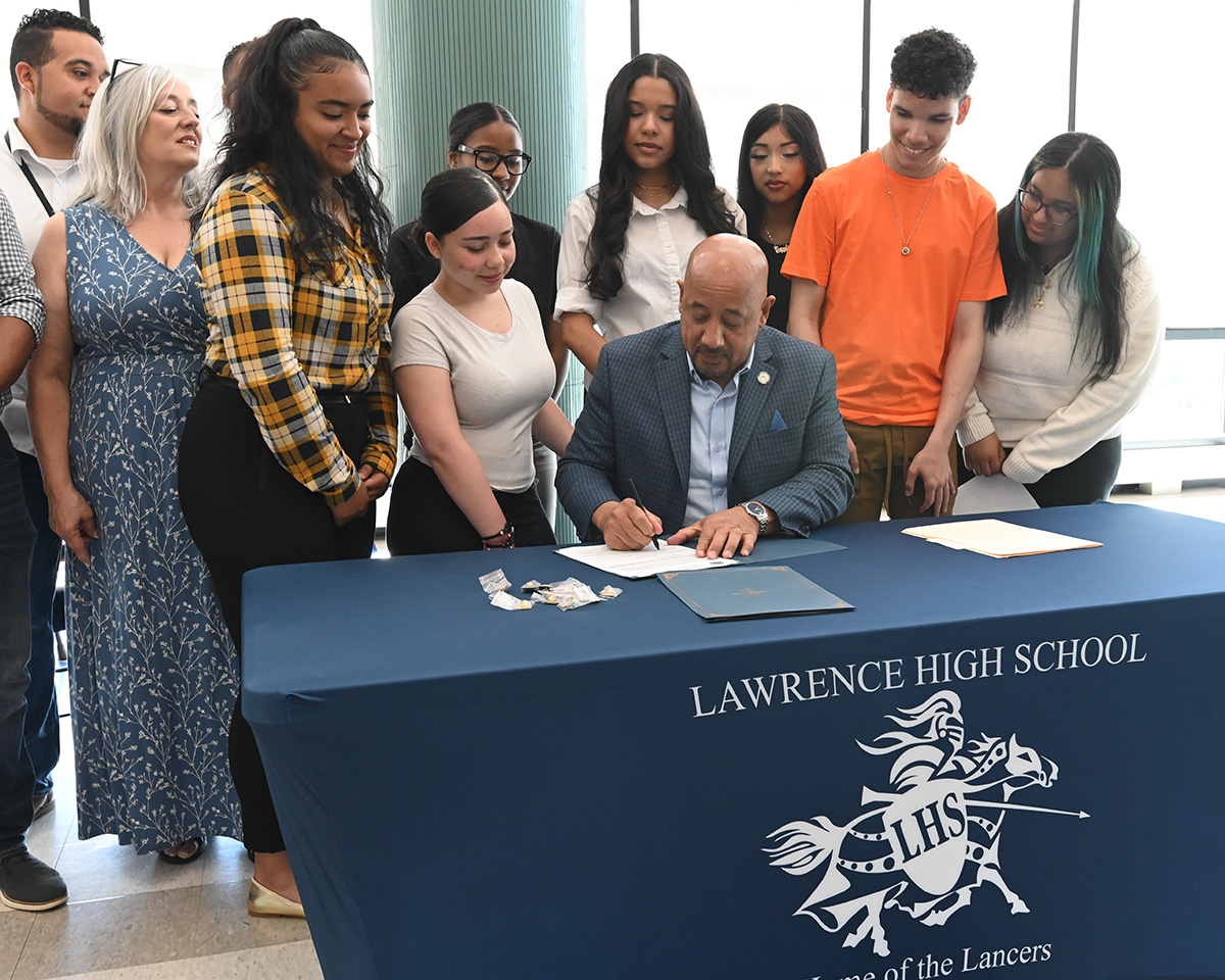 Mayor signing official document with students watching